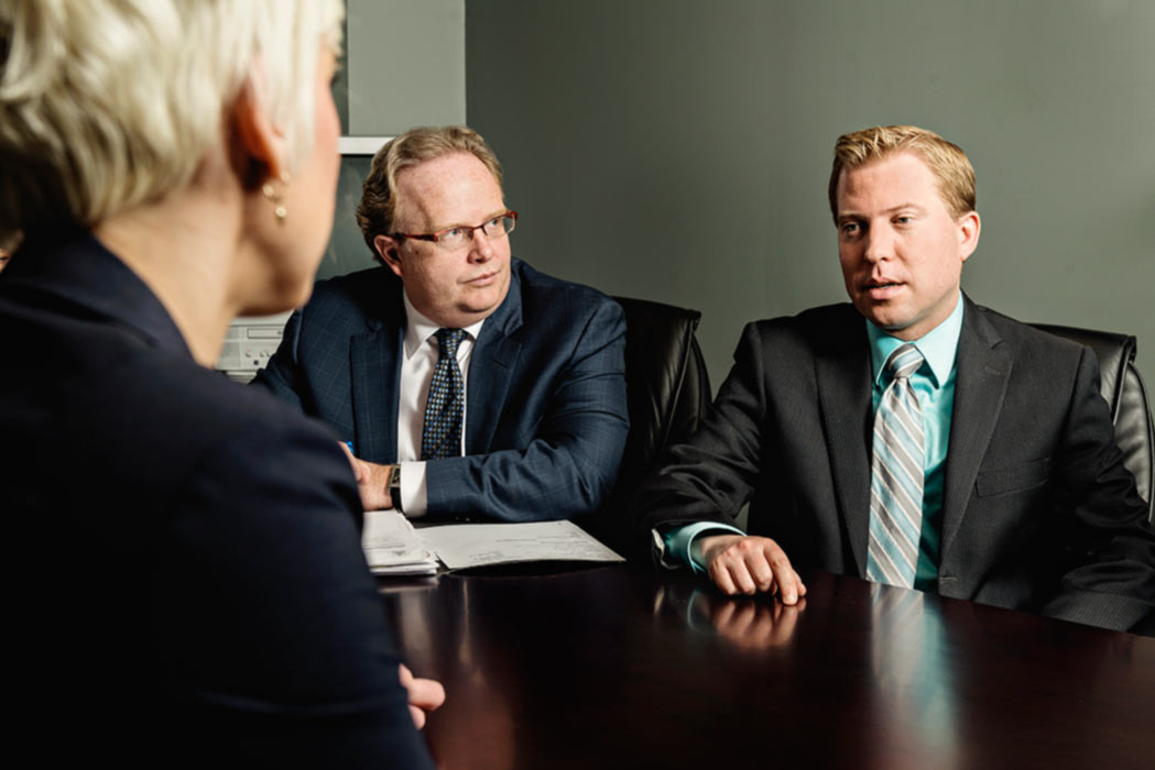 Three criminal trial lawyers discussing a case around a table
